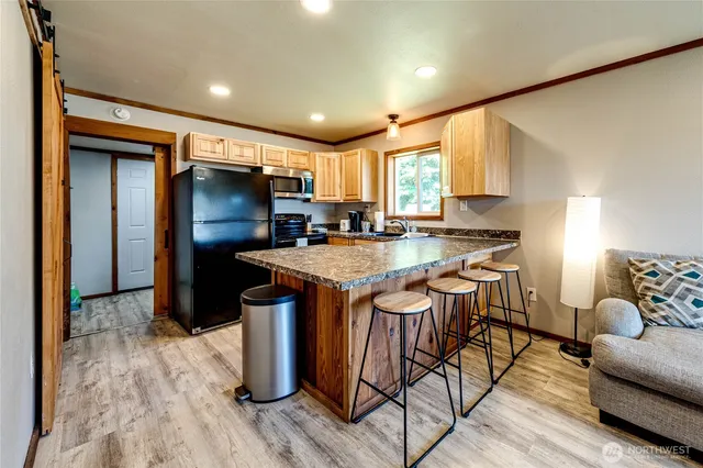 a kitchen with stainless steel appliances granite countertop a refrigerator a sink dishwasher a stove and a dining table with wooden floor