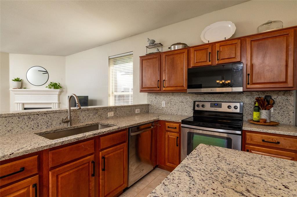 4025 Chisos Rim Trail Fort Worth, TX 76244 - Photo 15 of 40 Kitchen featuring warm wood cabinetry, stainless steel appliances, granite countertops, and a stainless steel sink with a gooseneck faucet