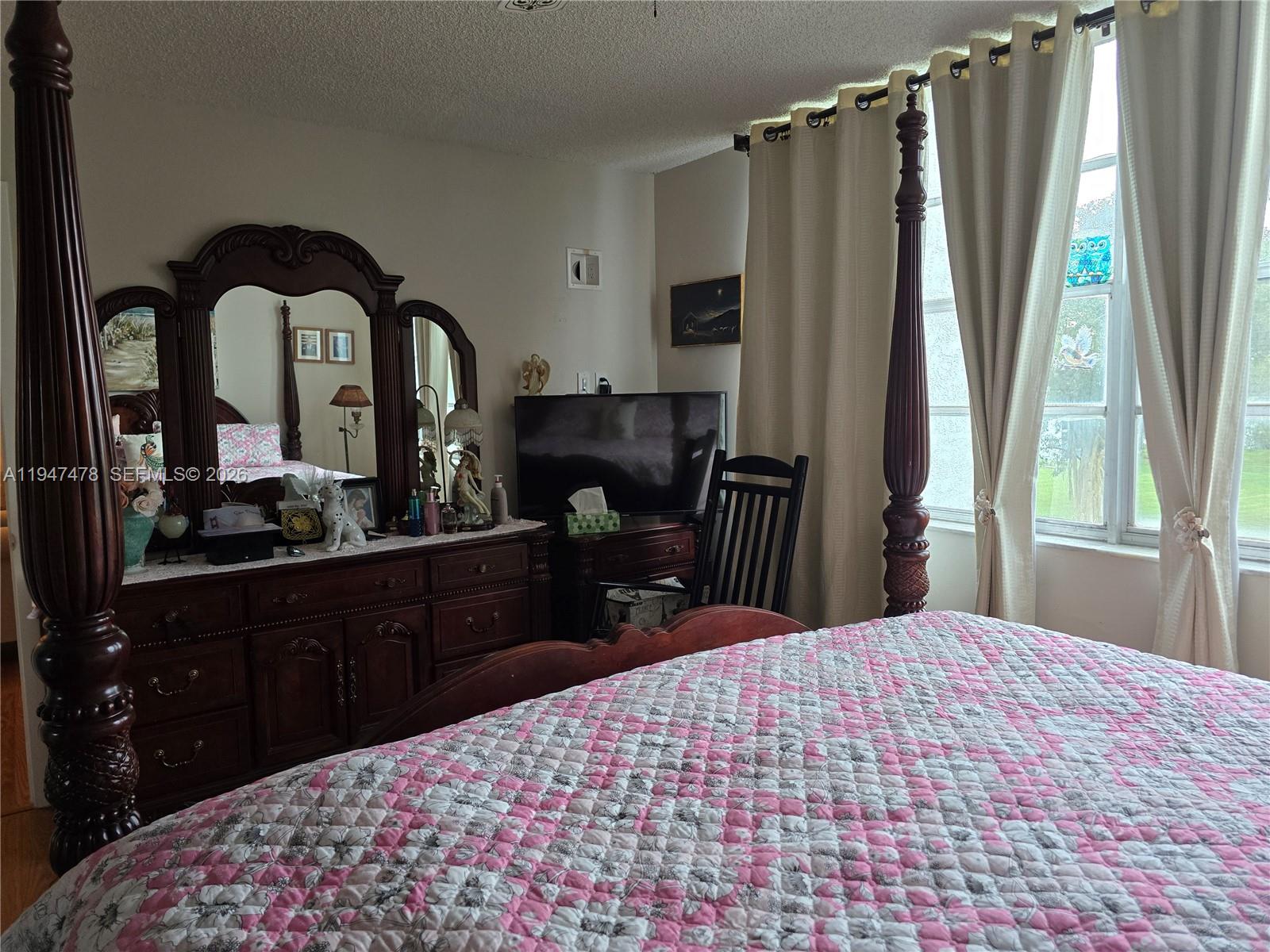 7690 Northwest 18th Street, Unit 306 Margate, FL 33063 - Photo 12 of 30 a bedroom with a bed and a dresser with mirror