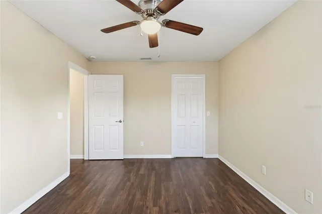 an empty room with wooden floor ceiling fan and window