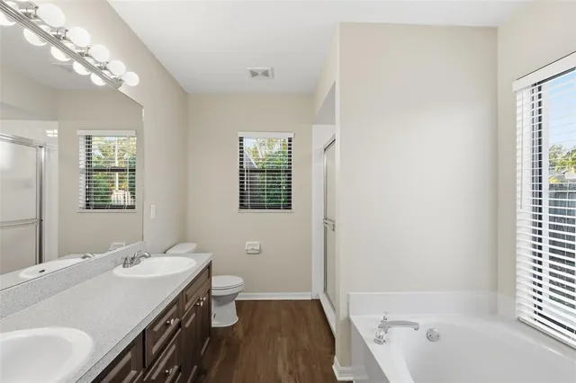 a bathroom with a sink a toilet a shower and a large mirror