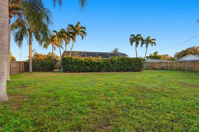 a view of house with garden space and palm trees