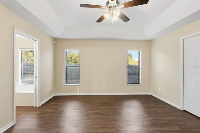 an empty room with wooden floor fan and windows