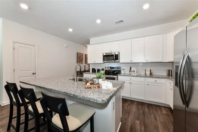 a kitchen with stainless steel appliances granite countertop a stove a sink dishwasher a microwave oven with a dining table and chairs