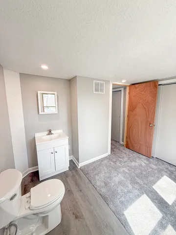 a bathroom with a granite countertop sink a toilet a mirror and shower