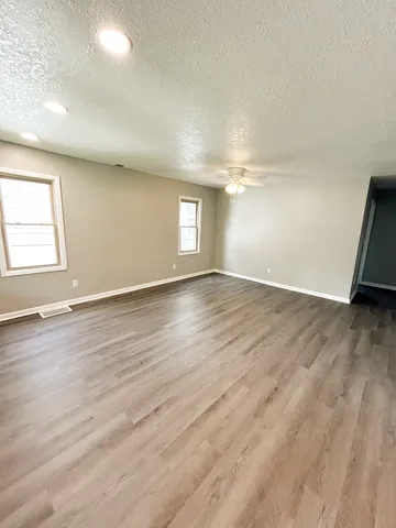 an empty room with wooden floor and windows