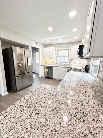 a large kitchen with a sink stainless steel appliances and furniture