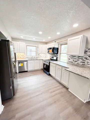 a large kitchen with a stove top oven a refrigerator a sink dishwasher with a dining table and chairs