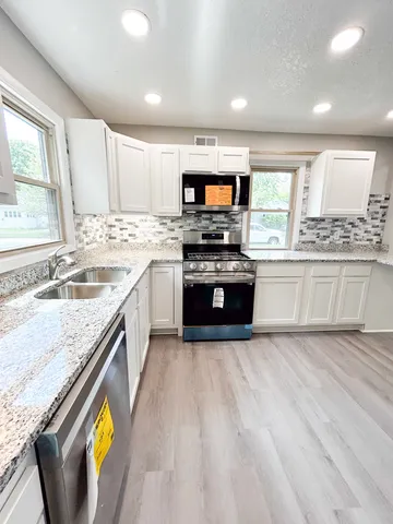 a large kitchen with stainless steel appliances granite countertop a stove and a sink