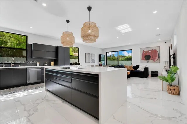 a large white kitchen with a large island oven a stove a dining table and chairs