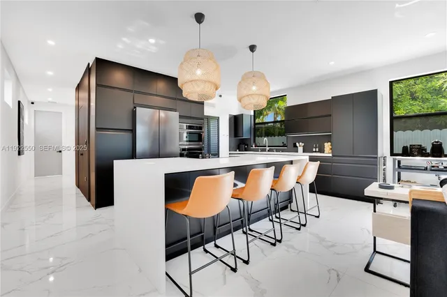 a kitchen with stainless steel appliances kitchen island granite countertop a table chairs and a refrigerator