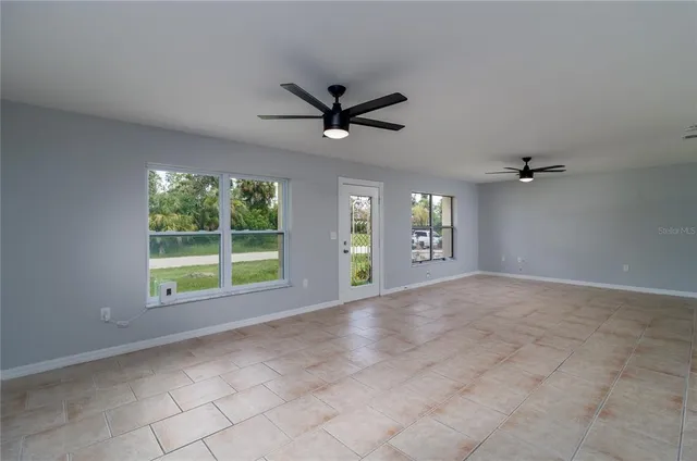 a view of an empty room with a ceiling fan and window