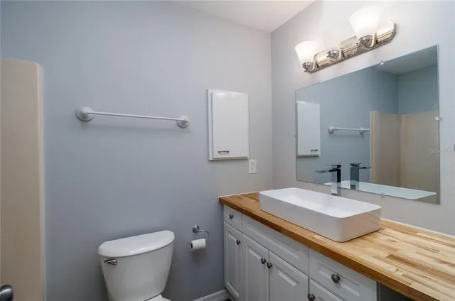 a bathroom with a granite countertop sink a toilet and mirror