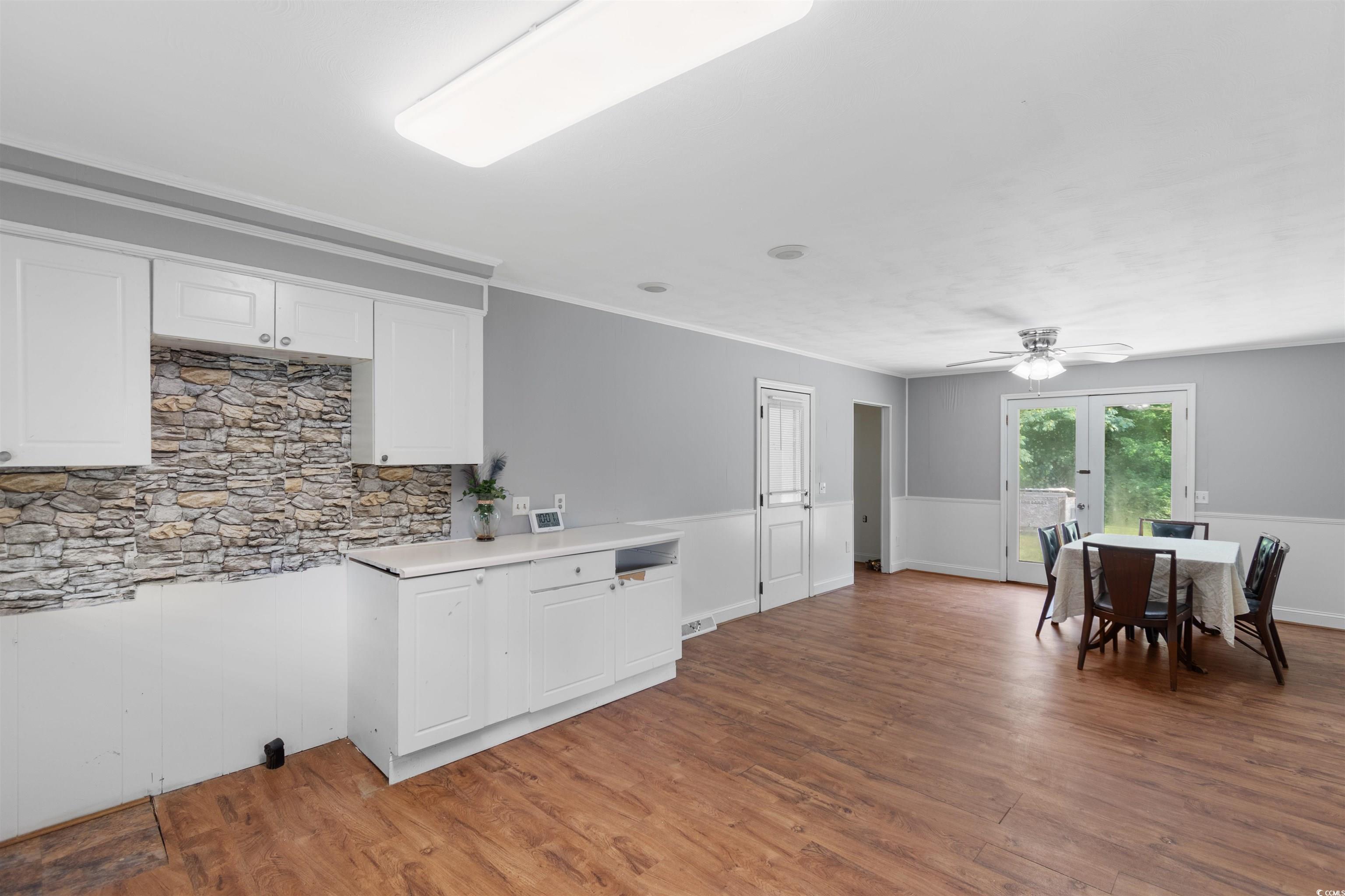 5 County Rd S-45-516 Hemingway, SC 29554 - Photo 12 of 30 Kitchen with light wood-type flooring, light countertops, white cabinets, ceiling fan, and a wainscoted wall