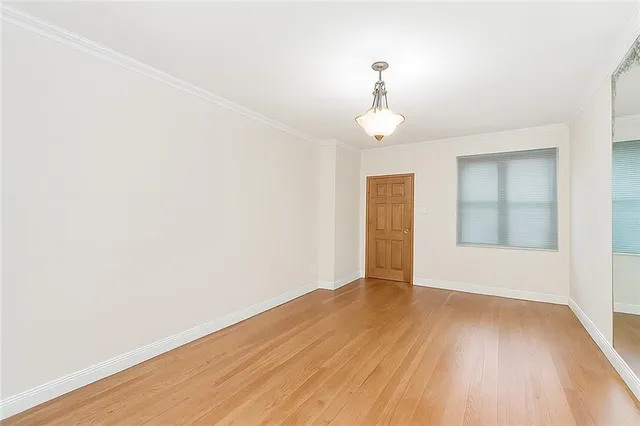 an empty room with wooden floor chandelier and windows