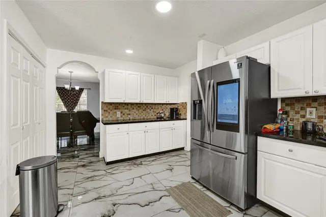 a kitchen with granite countertop a refrigerator and a stove top oven