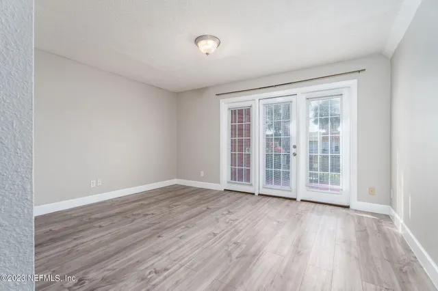 an empty room with wooden floor and windows