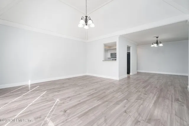 an empty room with wooden floor and chandelier fan