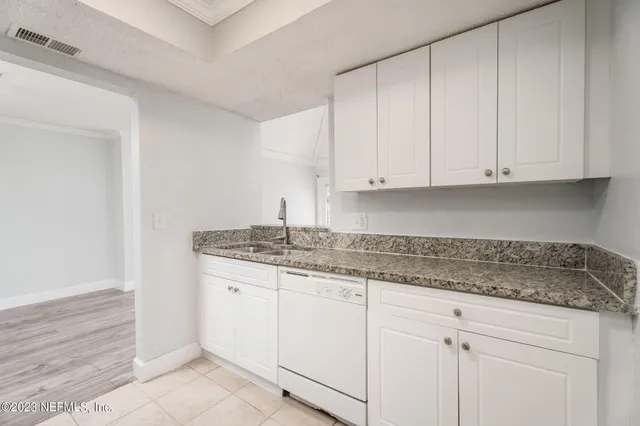 a kitchen with granite countertop white cabinets and a sink
