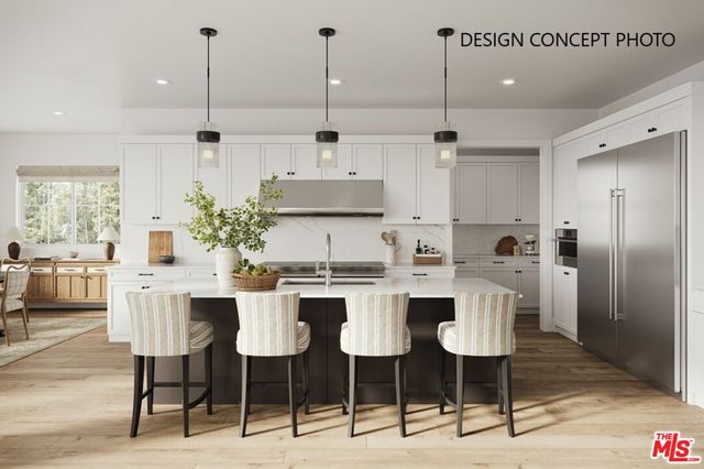 a kitchen with stainless steel appliances kitchen island granite countertop a dining table chairs and white cabinets