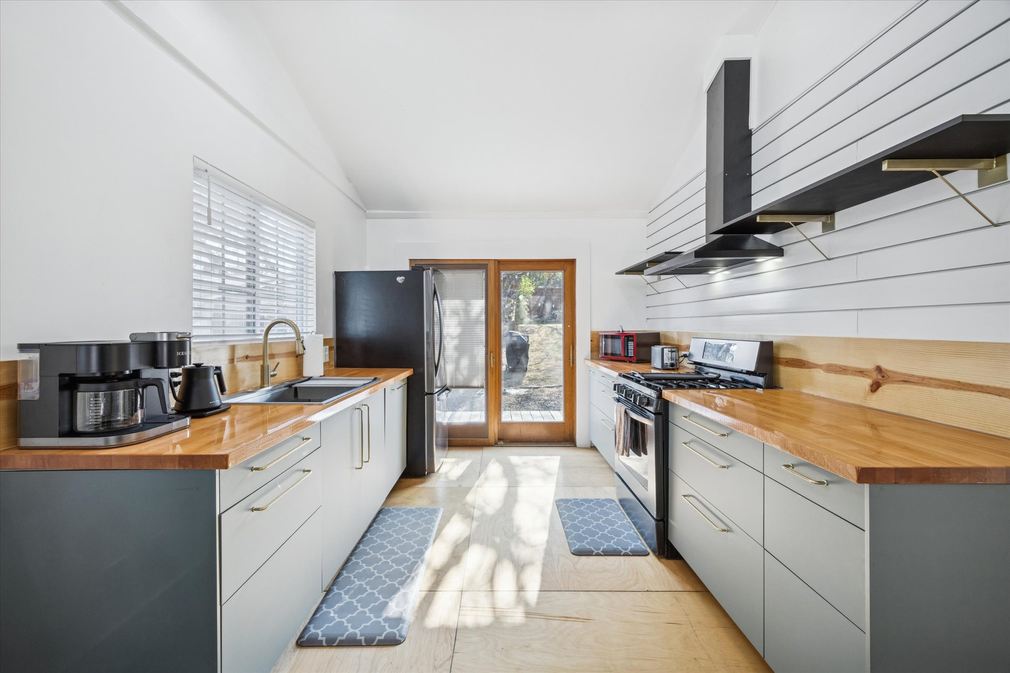 213 Lessin Lane Austin, TX 78704 - Photo 8 of 16 Kitchen featuring open shelves, stainless steel appliances, wooden counters, gray cabinets, and vaulted ceiling