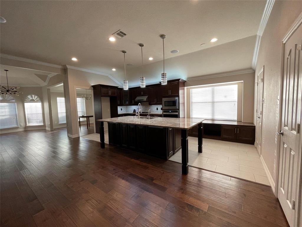 a kitchen with stainless steel appliances kitchen island granite countertop a stove a sink a refrigerator and a oven with wooden floor