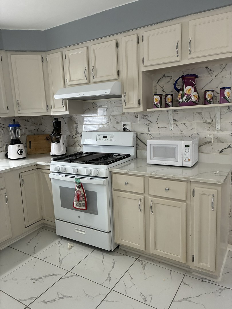 14622 Wabash Avenue Dolton, IL 60419 - Photo 12 of 18 a kitchen with white cabinets and appliances