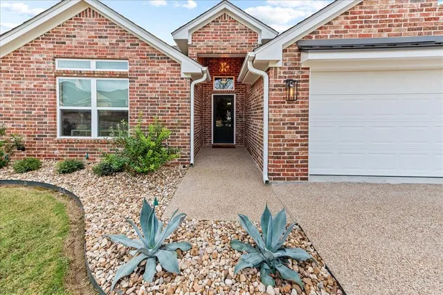 a front view of a house with a garden and yard