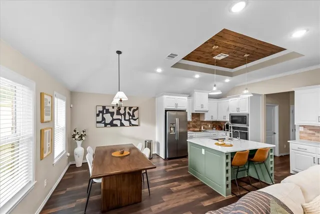 a kitchen with refrigerator a stove a sink and chairs