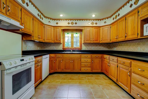a kitchen with granite countertop cabinets stainless steel appliances a sink and a window