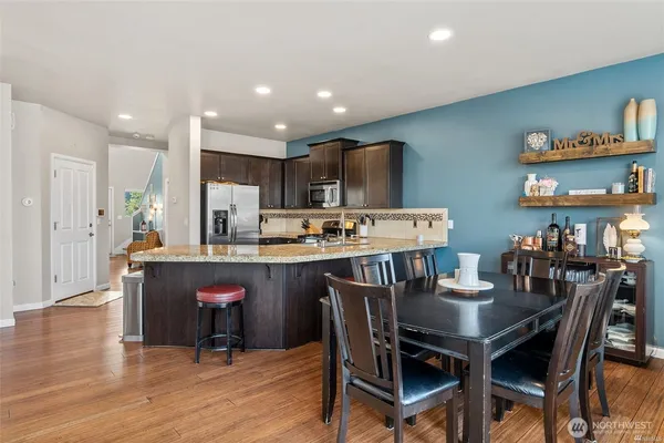a dining area with stainless steel appliances kitchen island granite countertop a dining table and chairs
