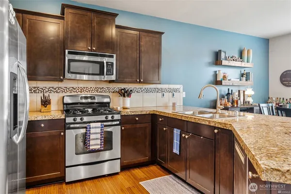 a kitchen with stainless steel appliances granite countertop a stove a sink and a microwave