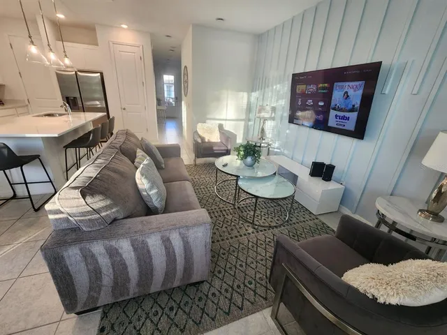 a living room with dining table a flat screen tv and couches