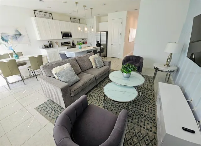 a kitchen with stainless steel appliances kitchen island granite countertop a sink a stove a refrigerator and white cabinets with wooden floor