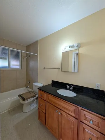 a bathroom with a granite countertop bathtub shower sink and toilet
