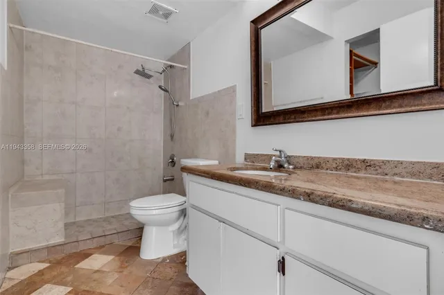 a bathroom with a granite countertop sink a toilet and a mirror