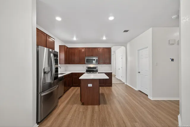 a large kitchen with a large counter top stainless steel appliances and wooden floor
