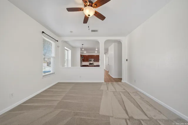 a view of an empty room with window and a kitchen