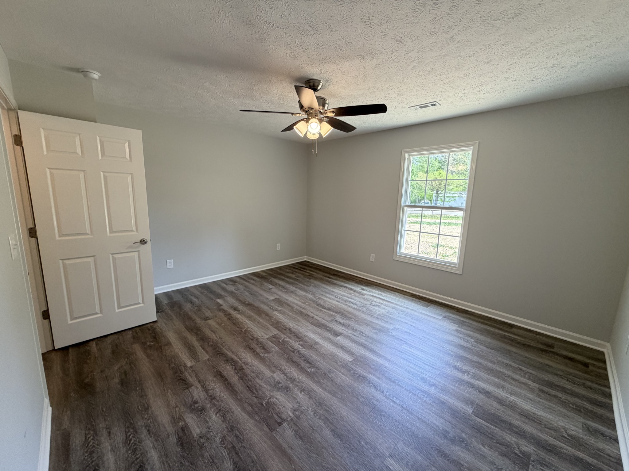 74 6 Mile Board Road Winchester, TN 37398 - Photo 63 of 99 an empty room with wooden floor ceiling fan and windows