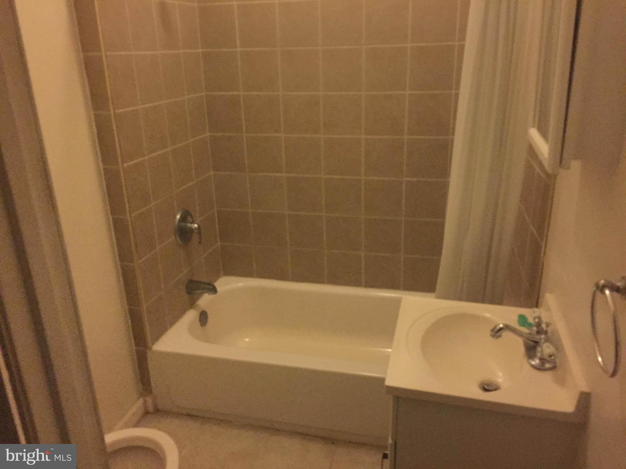2734 Harford Road Baltimore, MD 21218 - Photo 7 of 12 a white bath tub sitting next to a white sink and a shower