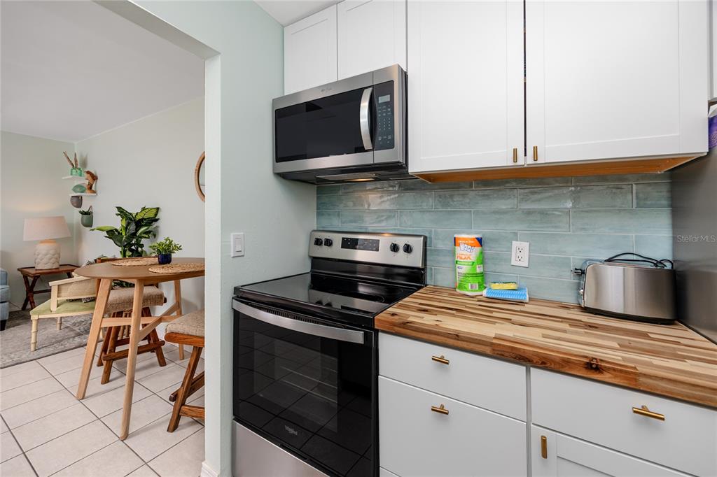 159 Medallion Boulevard, Unit H Madeira Beach, FL 33708 - Photo 16 of 57 a kitchen with stainless steel appliances granite countertop a stove a sink and a microwave