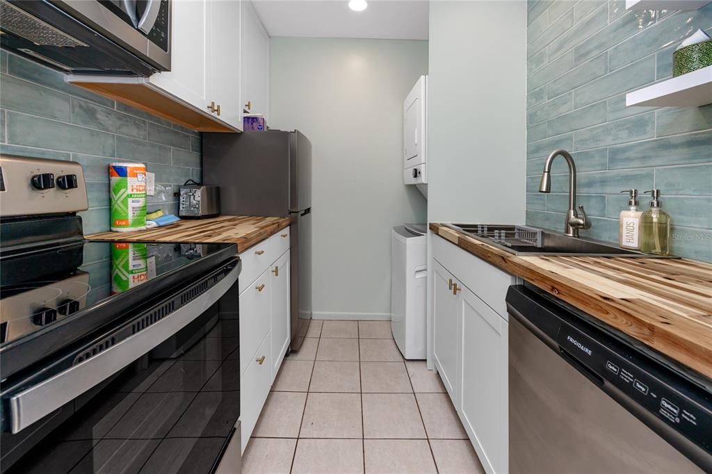 159 Medallion Boulevard, Unit H Madeira Beach, FL 33708 - Photo 19 of 57 a kitchen with stainless steel appliances granite countertop a sink and a stove