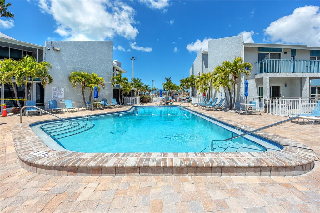 159 Medallion Boulevard, Unit H Madeira Beach, FL 33708 - Photo 33 of 57 a view of a swimming pool with a lounge chairs