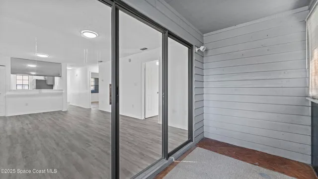 a view of a hallway with wooden floor and a bathroom