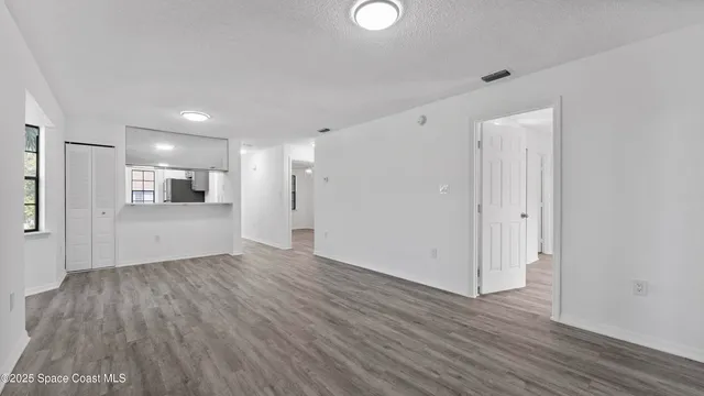 a view of a big room with wooden floor and a kitchen