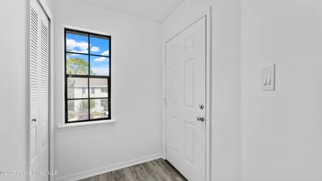 a view of an empty room with closet and windows