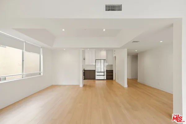 a view of empty room with kitchen and window