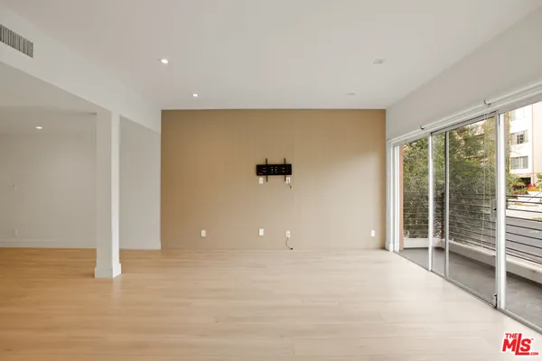 a view of an empty room with wooden floor and floor to ceiling window