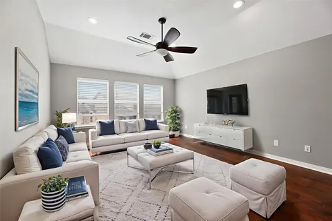a living room with furniture ceiling fan and a flat screen tv
