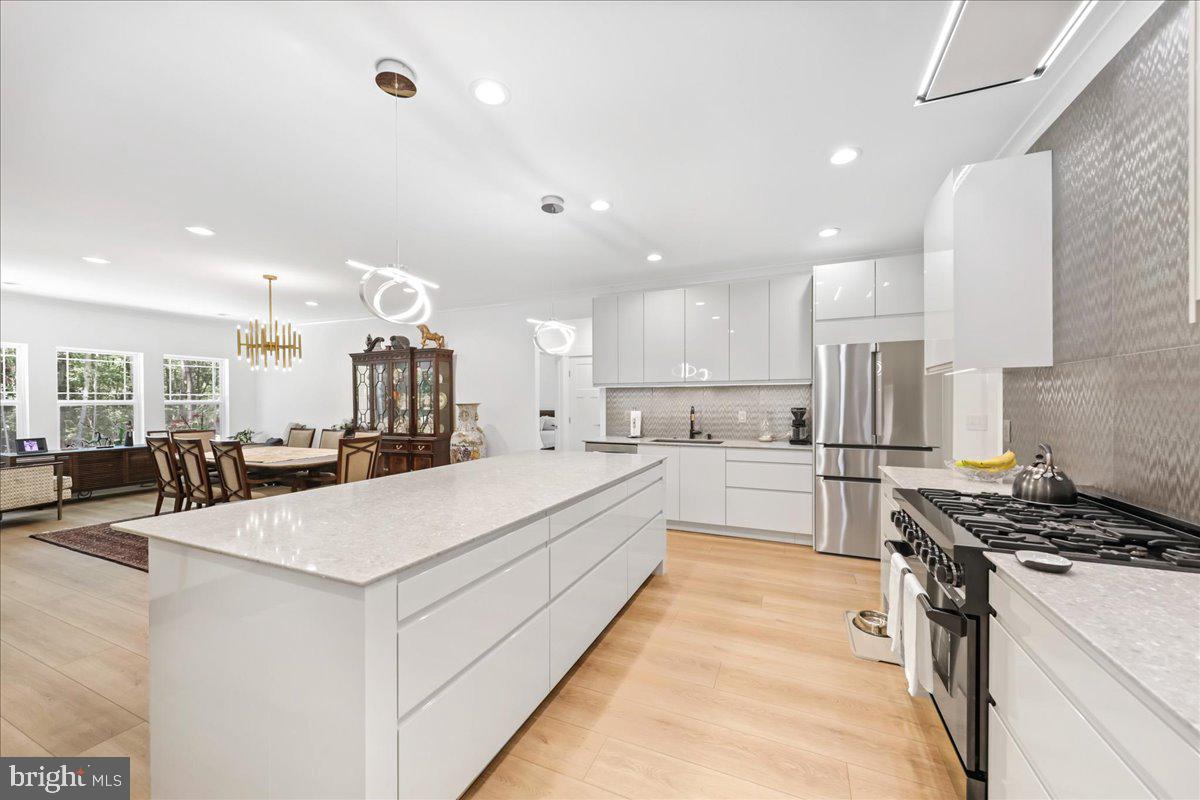 36755 Double Bridges Road Frankford, DE 19945 - Photo 6 of 38 a large white kitchen with kitchen island a stove a sink a refrigerator and white cabinets with wooden floor